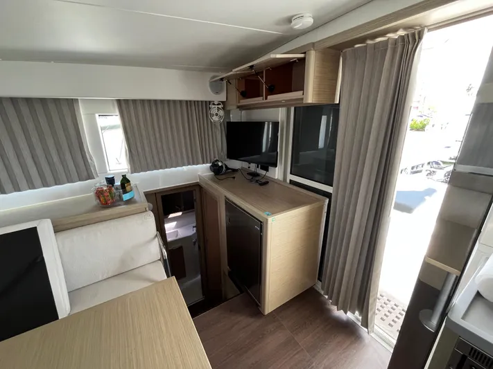  Yacht Photos Pics Interior of 2023 Lagoon 40 catamaran with modern furnishings and compact kitchen area.