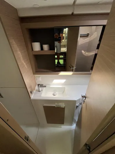 Yacht Photos Pics 2023 Lagoon 40 yacht bathroom with modern sink and wooden cabinetry.
