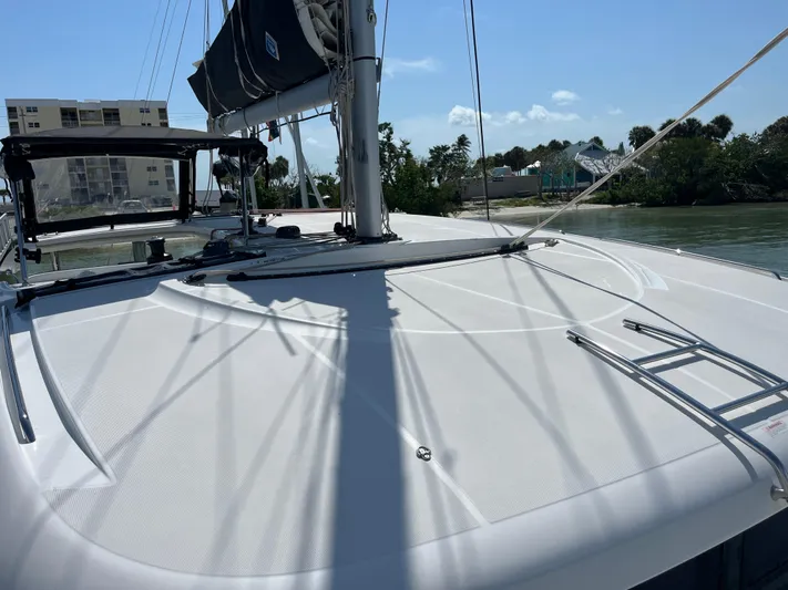  Yacht Photos Pics 2023 Lagoon 40 catamaran deck with sails, docked near buildings and trees.