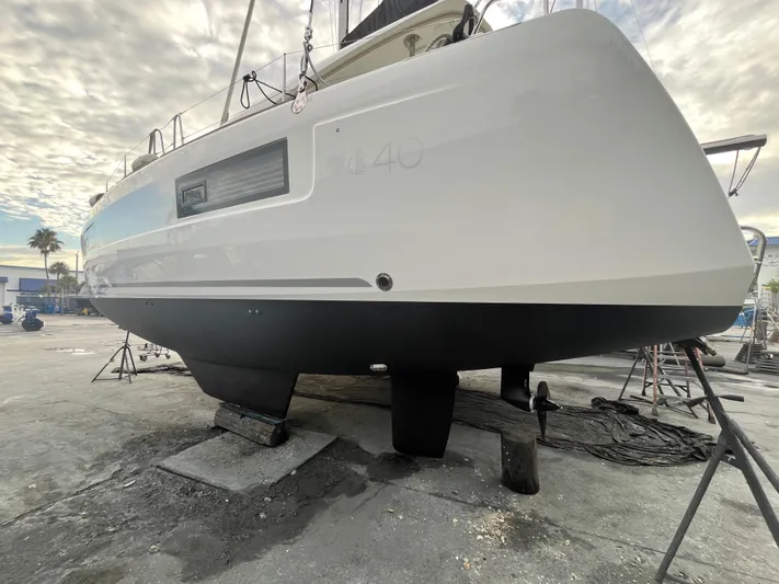  Yacht Photos Pics 2023 Lagoon 40 catamaran on dry dock, showcasing sleek hull design under cloudy sky.
