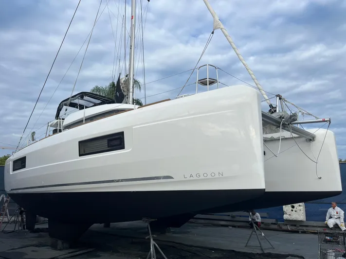  Yacht Photos Pics 2023 Lagoon 40 catamaran on dry dock under cloudy sky.