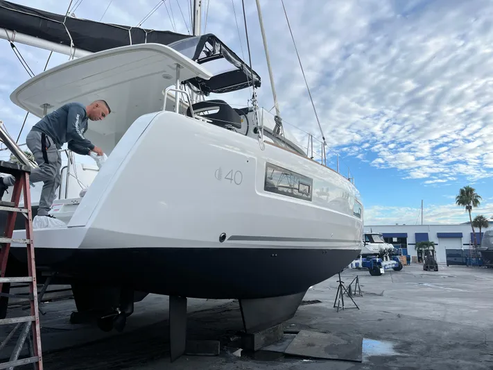  Yacht Photos Pics 2023 Lagoon 40 catamaran being serviced at a marina under a partly cloudy sky.
