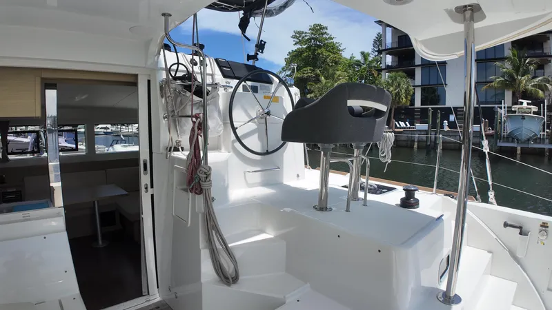  Yacht Photos Pics 2023 Lagoon 40 catamaran cockpit with steering wheel, docked near modern buildings.