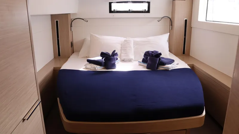 Happy Fluke Yacht Photos Pics Luxurious cabin interior of 2023 Lagoon 46 yacht with neatly arranged bed and towels.