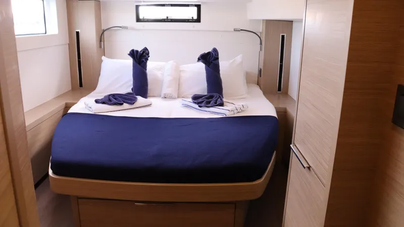 Happy Fluke Yacht Photos Pics Luxurious cabin interior of 2023 Lagoon 46 yacht with elegant bedding and modern design.