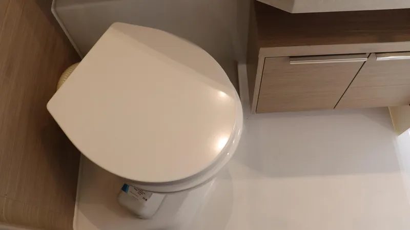 Happy Fluke Yacht Photos Pics Modern bathroom in 2023 Lagoon 46 yacht with sleek toilet and wooden cabinetry.