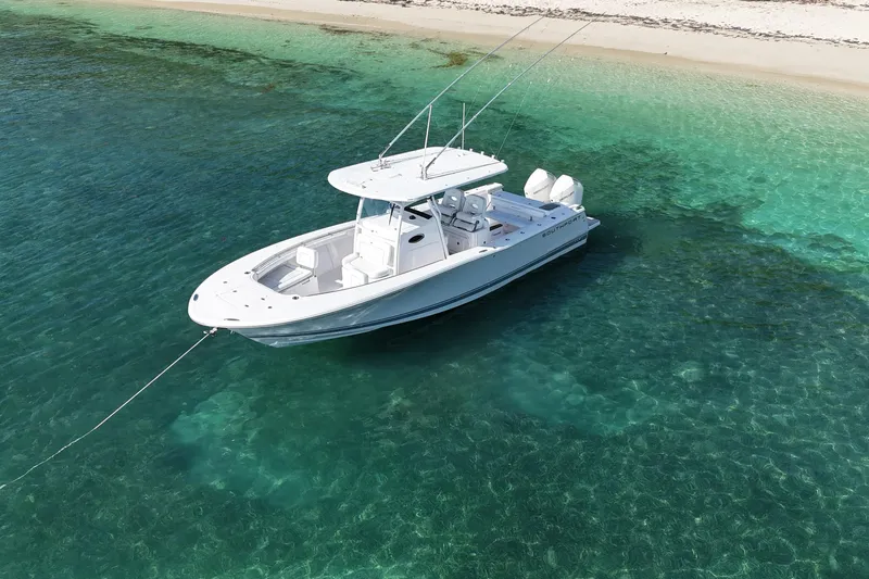  Yacht Photos Pics 2024 Southport 30 FE boat anchored in clear turquoise water near a sandy beach.