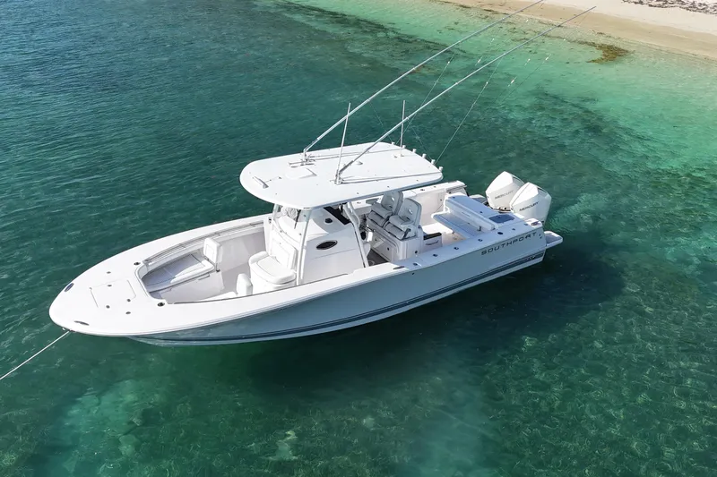  Yacht Photos Pics 2024 Southport 30 FE boat anchored in clear turquoise water near a sandy beach.