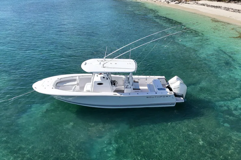  Yacht Photos Pics 2024 Southport 30 FE boat anchored in clear turquoise water near a sandy beach.