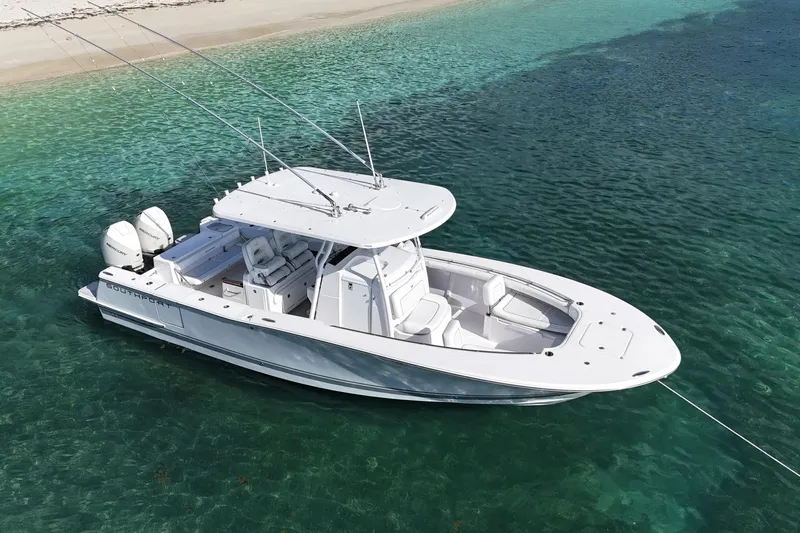  Yacht Photos Pics 2024 Southport 30 FE boat anchored in clear turquoise water near a sandy beach.