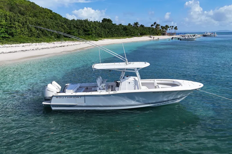  Yacht Photos Pics 2024 Southport 30 FE boat anchored in clear turquoise water near a sandy beach.