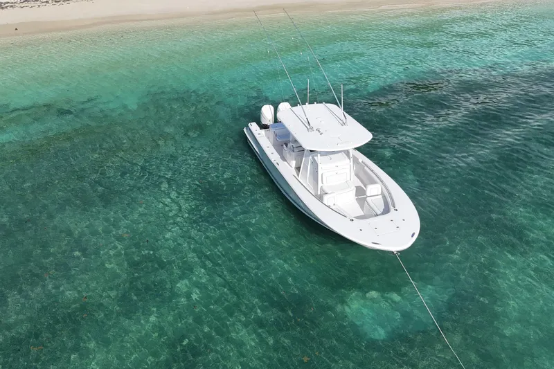  Yacht Photos Pics 2024 Southport 30 FE boat anchored in clear turquoise waters near a sandy beach.