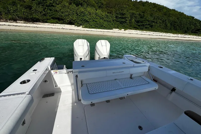  Yacht Photos Pics 2024 Southport 30 FE boat with dual engines, docked near a sandy beach and lush greenery.