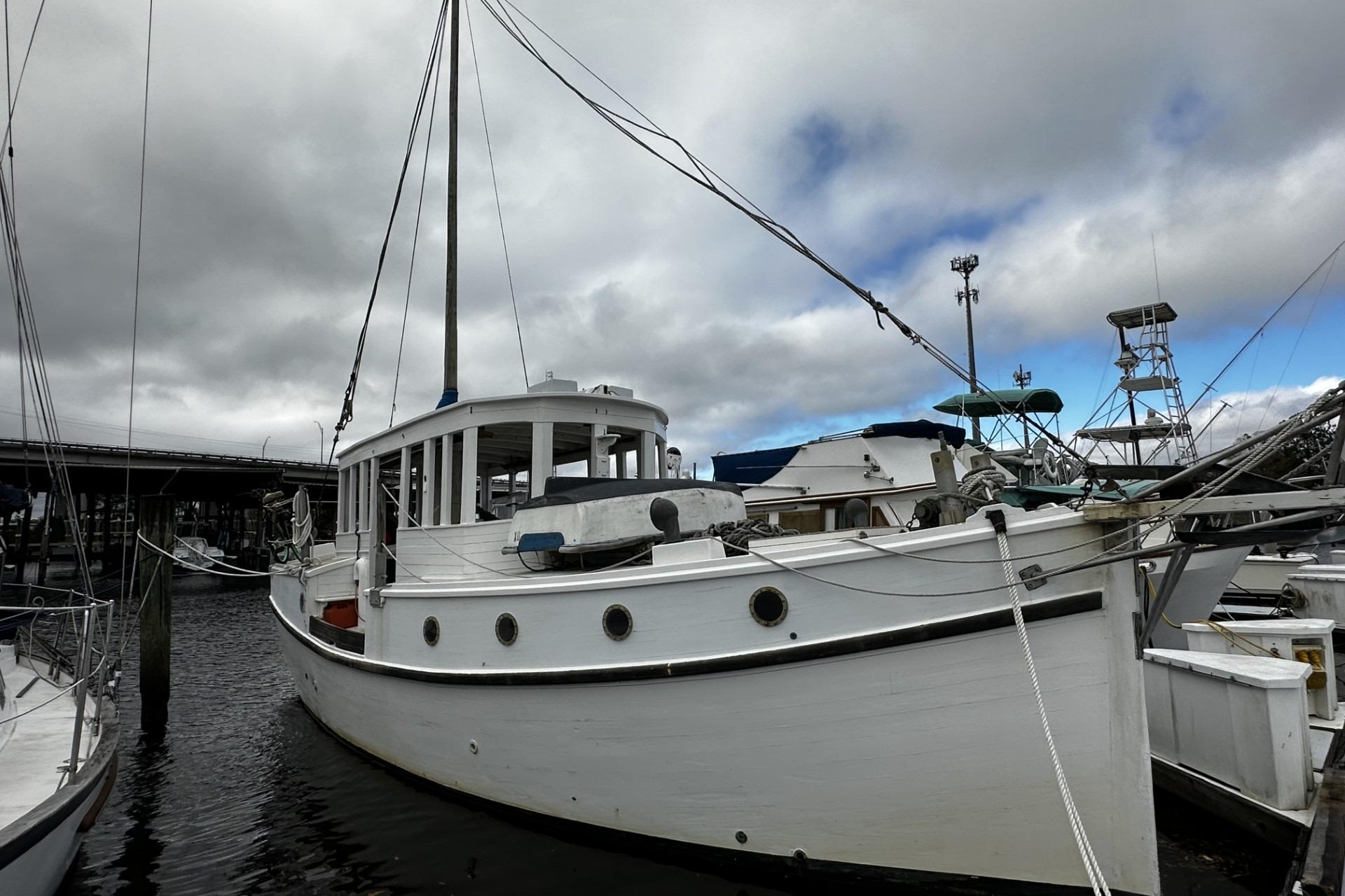 Custom 2005 sail-assisted trawler docked under cloudy skies.