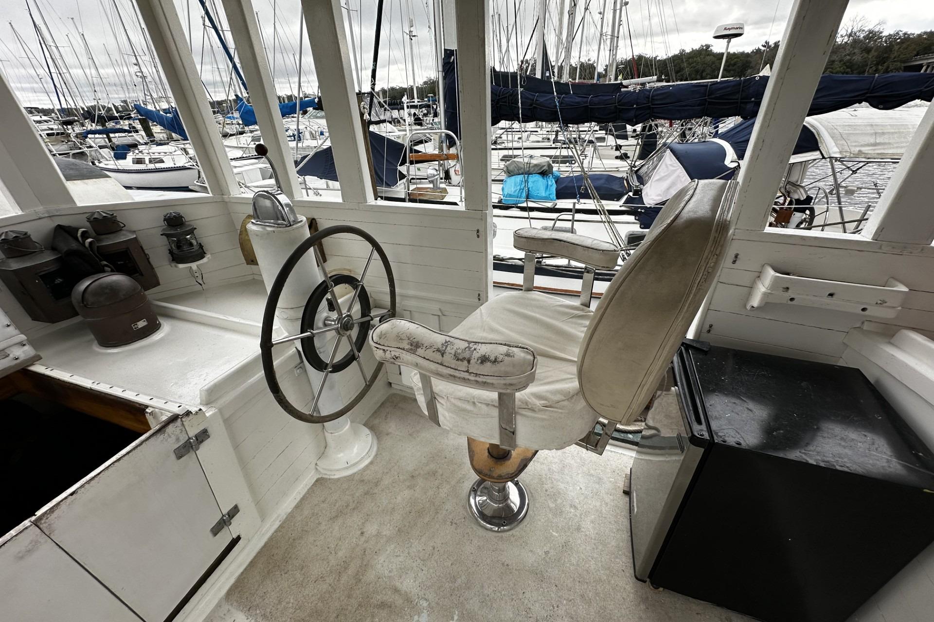 Helm of 2005 Custom Sail-Assisted Trawler with vintage steering wheel and captain's chair.