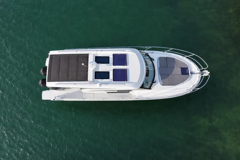 Slack Tide Yacht Photos Pics Top view of 2022 Beneteau Antares 11 Coupe on clear green water.