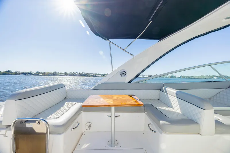 Sol Mates Yacht Photos Pics 2013 Sea Ray 370 Venture boat interior with sunlit seating and table on a calm water backdrop.
