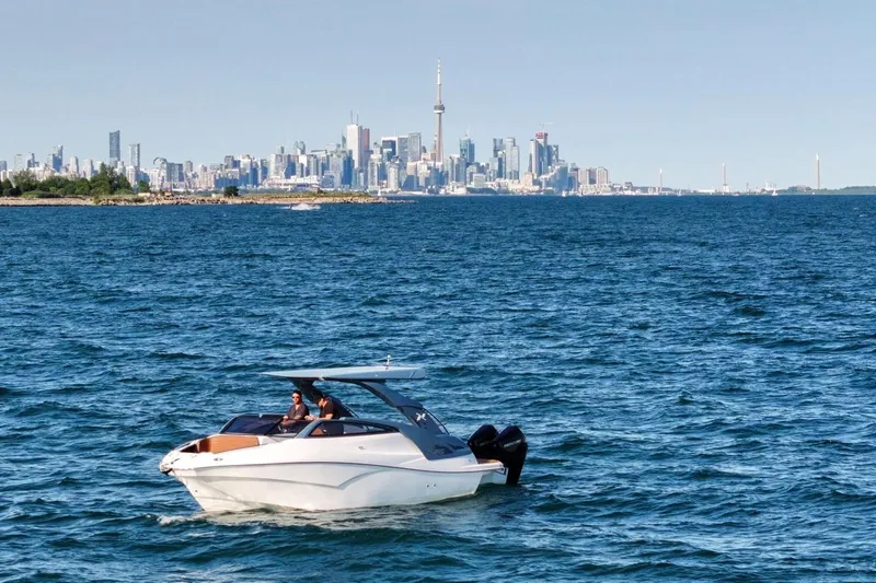  Yacht Photos Pics 2024 NX 280 Xtreme boat cruising on water with city skyline in background.