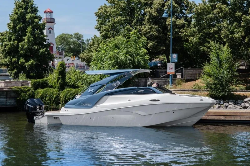  Yacht Photos Pics 2024 NX 280 Xtreme boat docked near a lighthouse, surrounded by lush greenery.