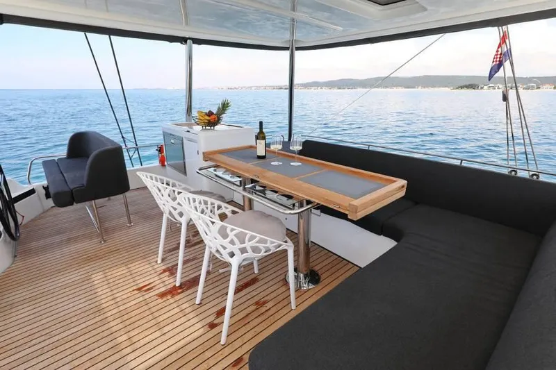  Yacht Photos Pics Luxurious 2023 Lagoon 55 yacht deck with dining area, ocean view, and modern seating.
