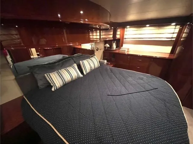 Juli's Priority Yacht Photos Pics Luxurious bedroom interior of a 2004 Marquis 59 yacht with elegant wood finishes.