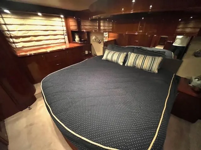 Juli's Priority Yacht Photos Pics Luxurious bedroom interior of a 2004 Marquis 59 yacht with elegant wood finishes.