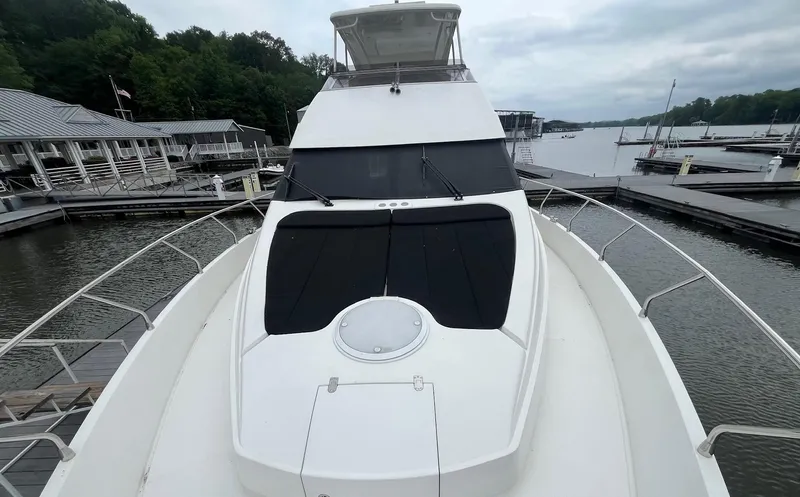 Juli's Priority Yacht Photos Pics 2004 Marquis 59 yacht docked at a marina, surrounded by calm waters and lush greenery.