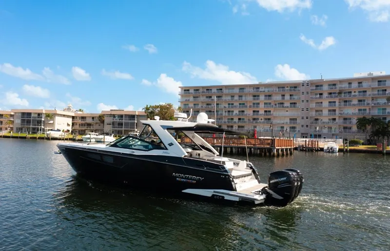  Yacht Photos Pics 2020 Monterey 385 Super Express yacht cruising near waterfront buildings under a clear blue sky.