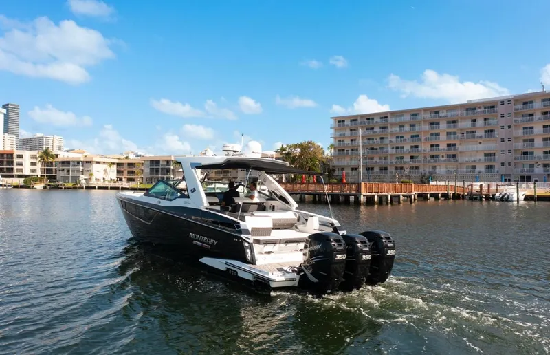  Yacht Photos Pics 2020 Monterey 385 Super Express boat cruising near waterfront buildings under blue sky.