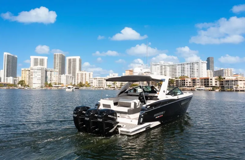  Yacht Photos Pics 2020 Monterey 385 Super Express boat cruising near city skyline under blue sky.