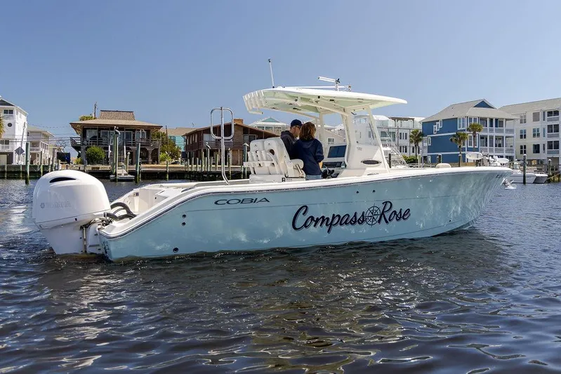 Compass Rose Yacht Photos Pics 2020 Cobia 280 Center Console boat on water, named "Compass Rose," near waterfront homes.