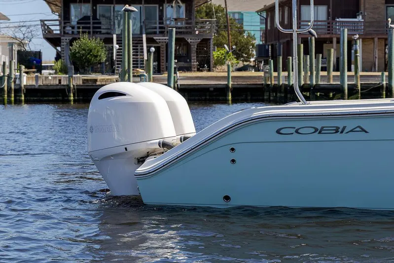 Compass Rose Yacht Photos Pics 2020 Cobia 280 Center Console boat with outboard motor, docked near waterfront homes.