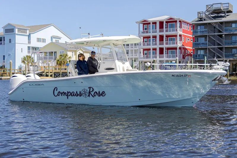 Compass Rose Yacht Photos Pics 2020 Cobia 280 Center Console boat named "Compass Rose" on water near colorful waterfront buildings.