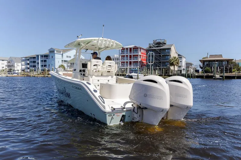 Compass Rose Yacht Photos Pics 2020 Cobia 280 Center Console boat cruising on water near waterfront buildings.