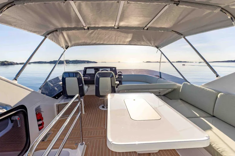  Yacht Photos Pics Luxurious 2026 Nimbus 495 Flybridge yacht interior with seating and table, overlooking serene waters.