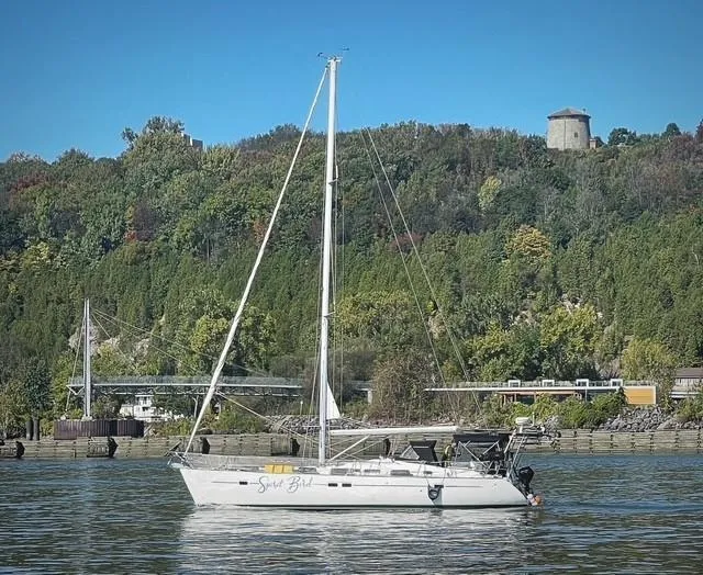 Spirit Bird Yacht Photos Pics 2004 Beneteau Oceanis 423 sailboat on calm water with lush green hillside background.