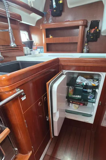 Spirit Bird Yacht Photos Pics Galley of 2004 Beneteau Oceanis 423 with open fridge, wooden cabinetry, and sink.