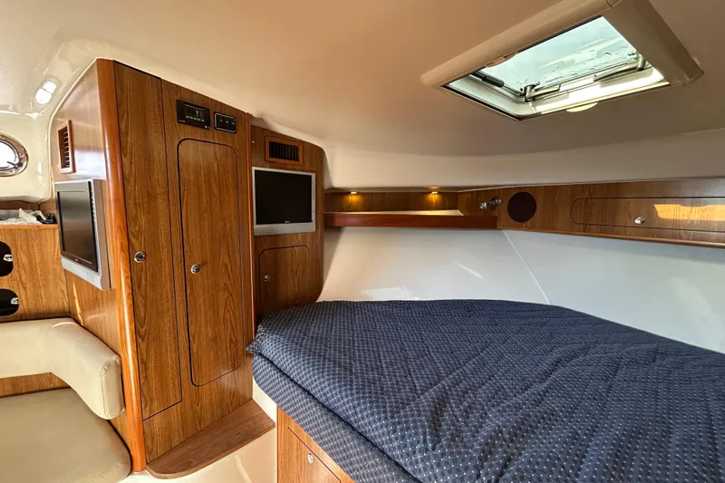  Yacht Photos Pics 2009 Pursuit OS 375 Offshore cabin interior with wood finish and cozy bedding.