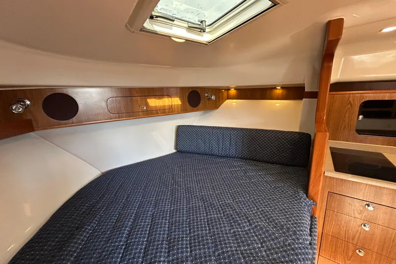  Yacht Photos Pics 2009 Pursuit OS 375 Offshore cabin interior with wood accents and cozy bedding.