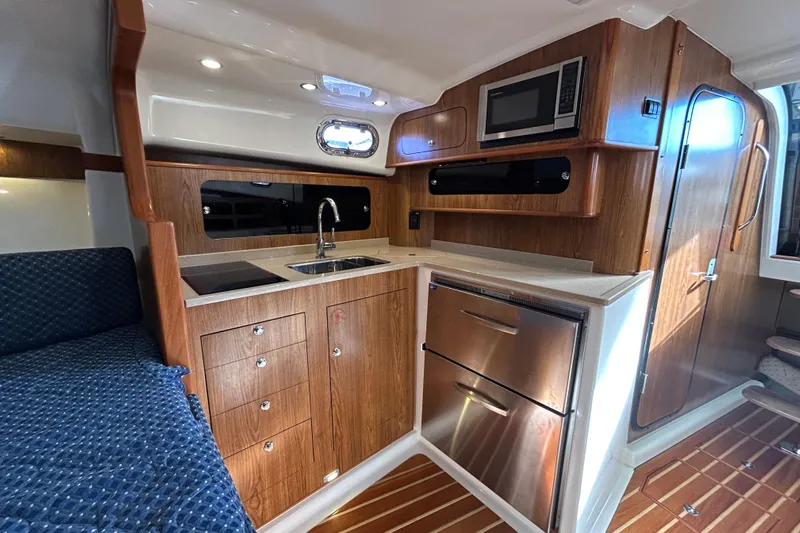  Yacht Photos Pics 2009 Pursuit OS 375 Offshore yacht interior with kitchenette, featuring wood cabinetry and modern appliances.