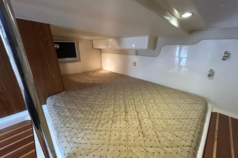  Yacht Photos Pics 2009 Pursuit OS 375 Offshore cabin interior with cozy bed and wooden accents.