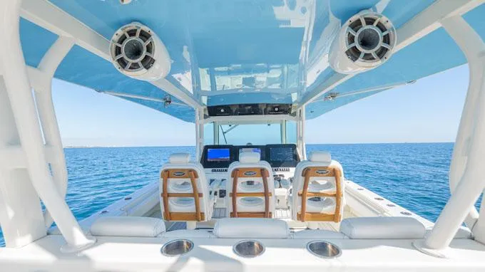 Reel Addiction Yacht Photos Pics Interior view of 2016 HCB Suenos 53 boat with blue canopy and ocean backdrop.