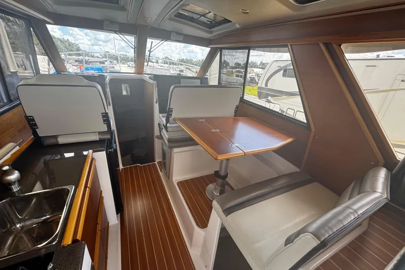 Happy Ours Yacht Photos Pics 2019 Cutwater C-28 interior with dining area, kitchenette, and wood accents.