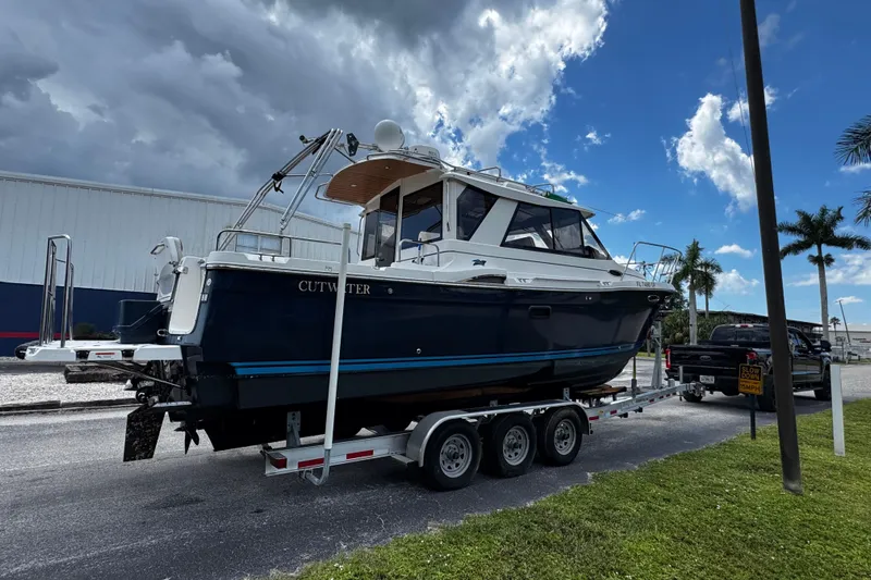 Happy Ours Yacht Photos Pics 2019 Cutwater C-28 boat on trailer under cloudy sky, parked near palm trees.