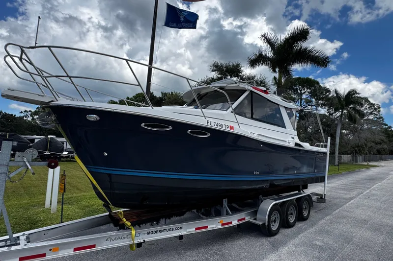 Happy Ours Yacht Photos Pics 2019 Cutwater C-28 boat on trailer, parked outdoors with palm trees and cloudy sky.