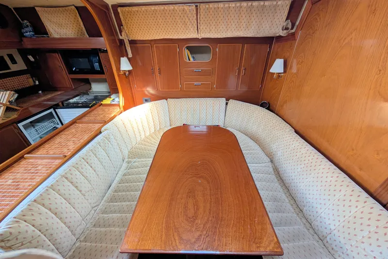 Iteration Yacht Photos Pics Interior of 1994 Amel 53 Super Maramu yacht with cozy dining area and wooden finishes.