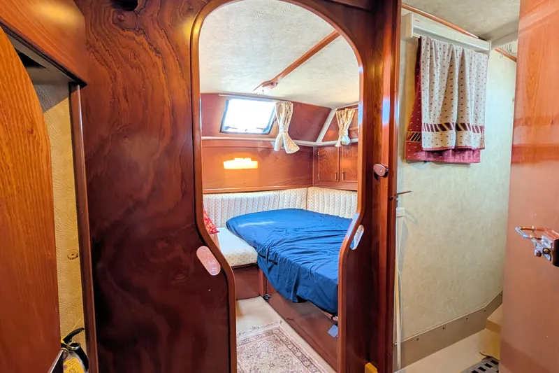 Iteration Yacht Photos Pics Cozy cabin interior of 1994 Amel 53 Super Maramu sailboat with wood finish and blue bedding.