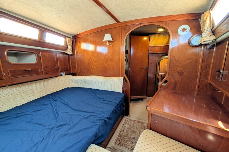 Iteration Yacht Photos Pics Interior of 1994 Amel 53 Super Maramu yacht with wood paneling and cozy bed.