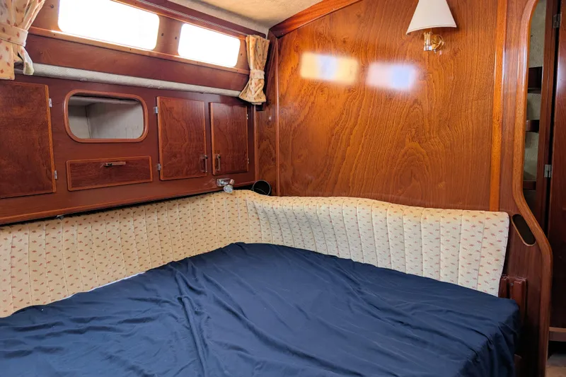 Iteration Yacht Photos Pics Cozy cabin interior of 1994 Amel 53 Super Maramu sailboat with wood paneling and bedding.