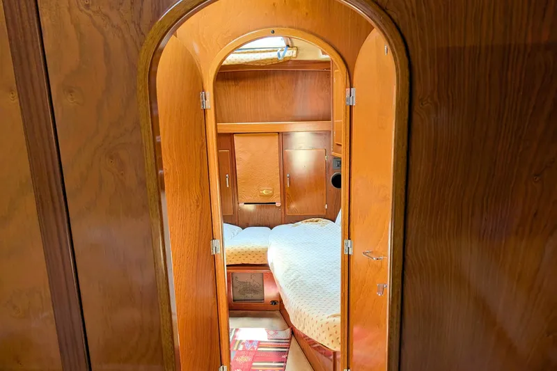 Iteration Yacht Photos Pics Interior of 1994 Amel 53 Super Maramu yacht cabin with wooden finish and cozy bed.
